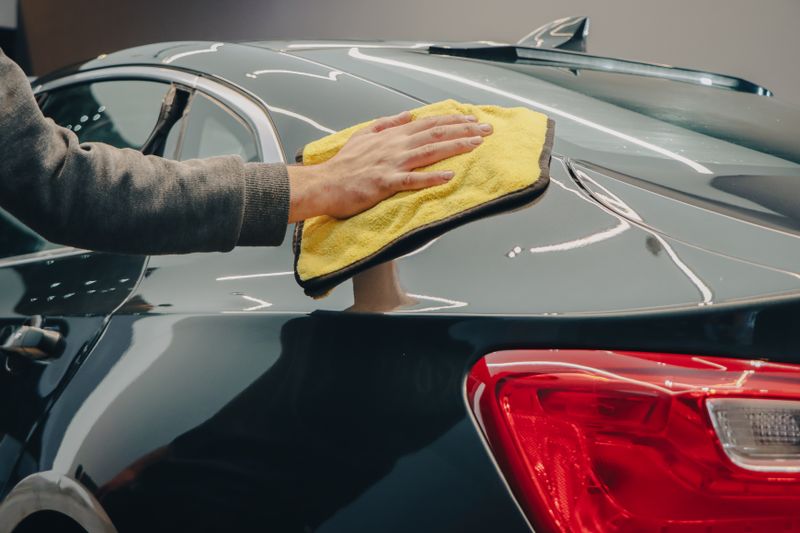 hand polishing shiny car paint with cloth