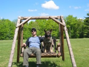 Kara, a German Shepherd, resting by her owner on a backyard garden swing