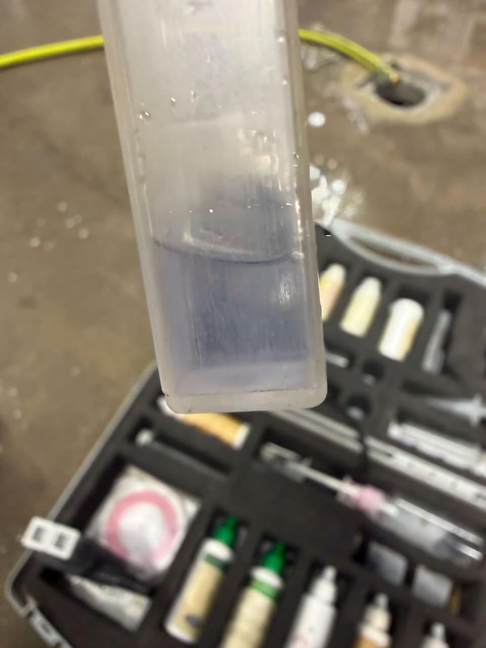 Close-up of a test tube with liquid, blurred background of a black case with medical supplies.