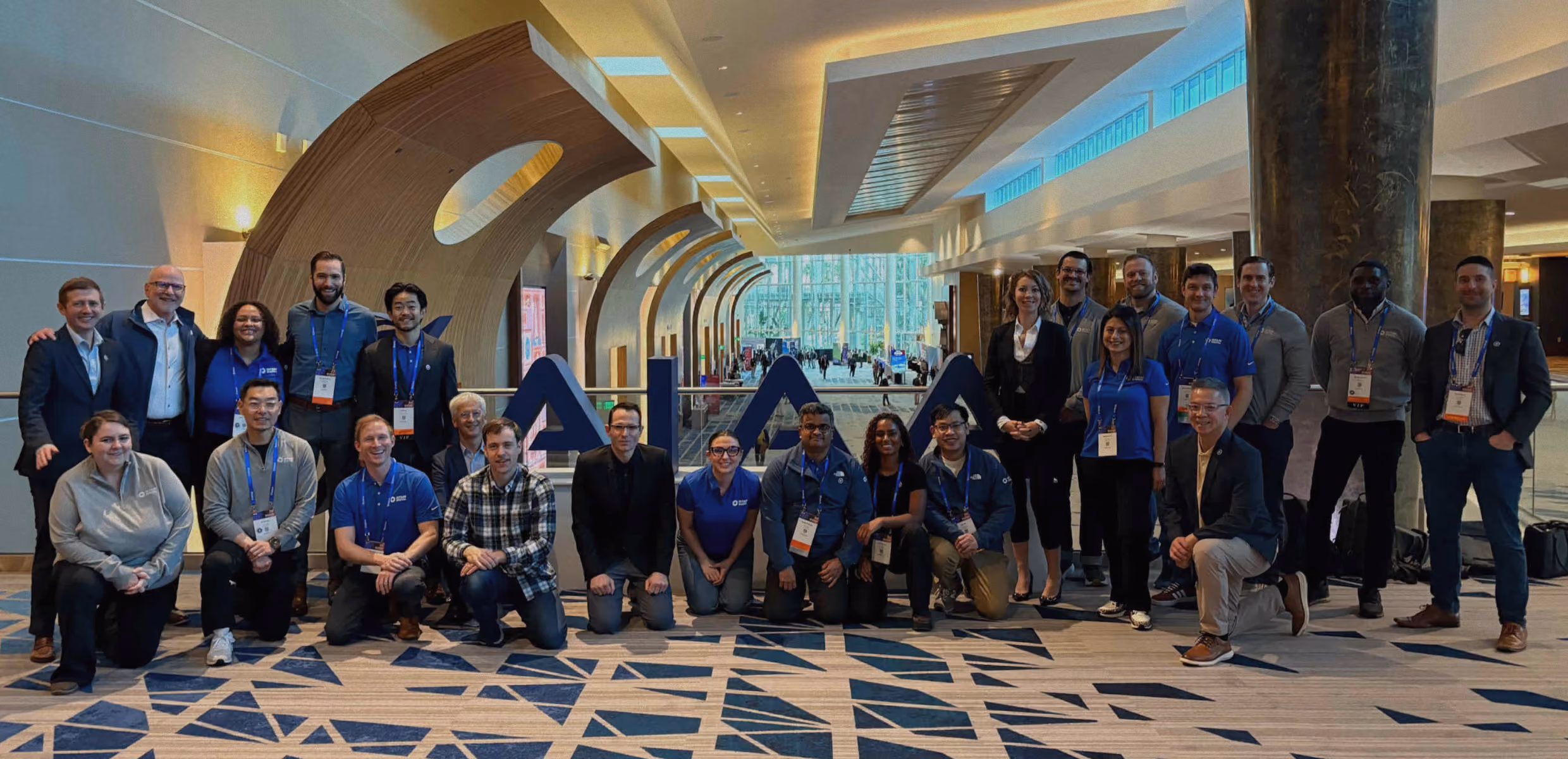 Group of professionals posing in a conference hall with large letters 'AI' behind them.