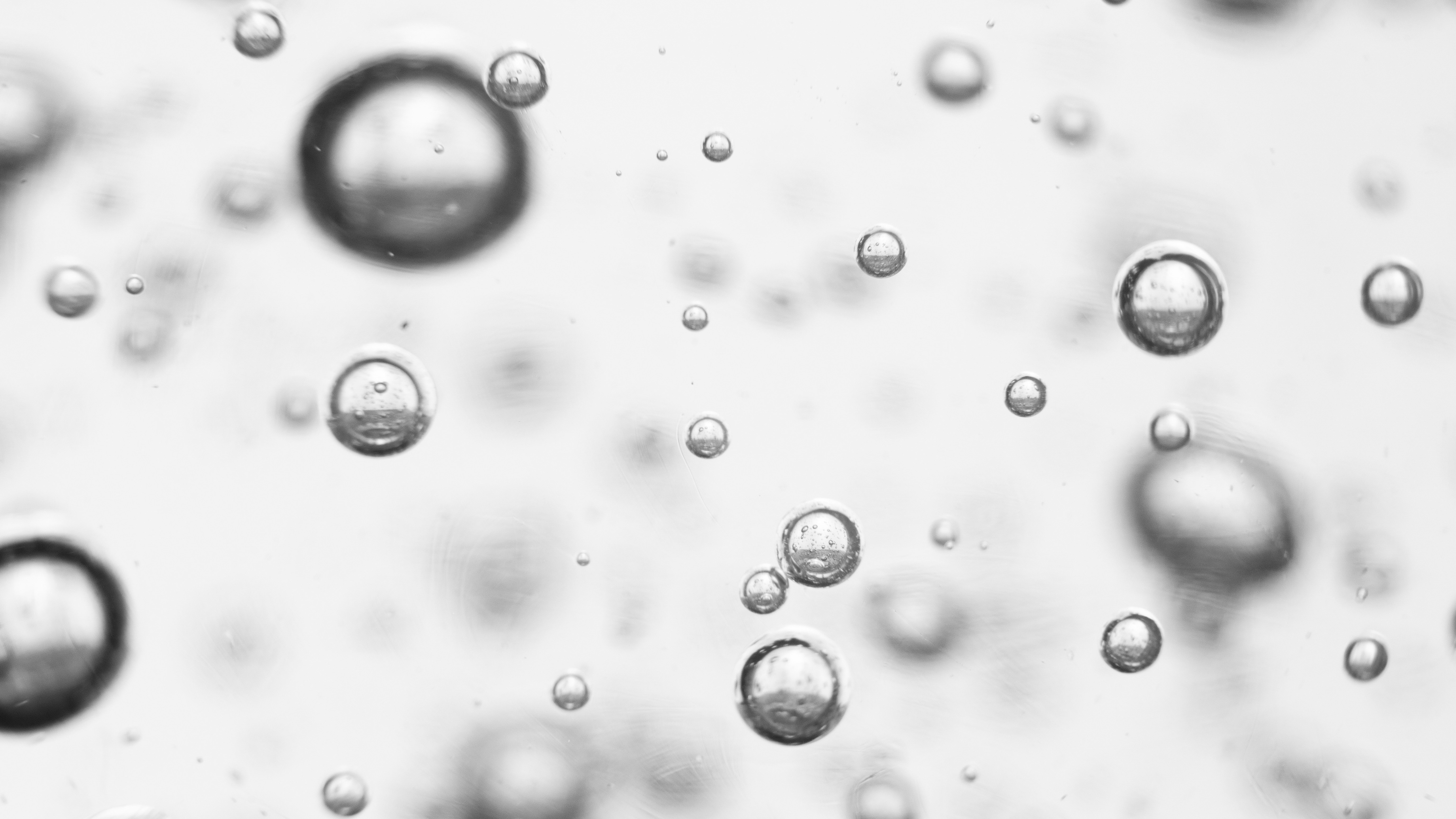 A hand reaching up toward distorted reflections on a water surface in black and white.