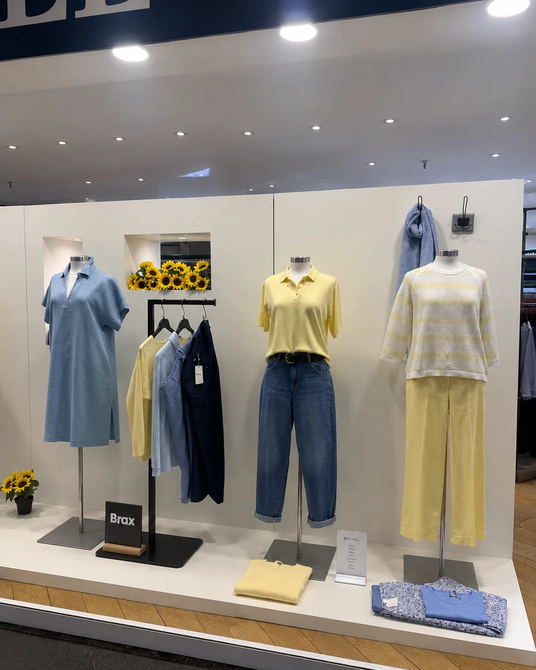 Vitrine de la boutique dame : tenues jaune pâle et bleu ciel, tournesols