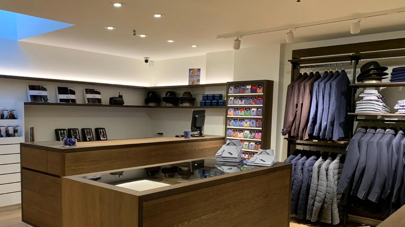 Intérieur de la boutique homme : comptoir en chêne et portants
