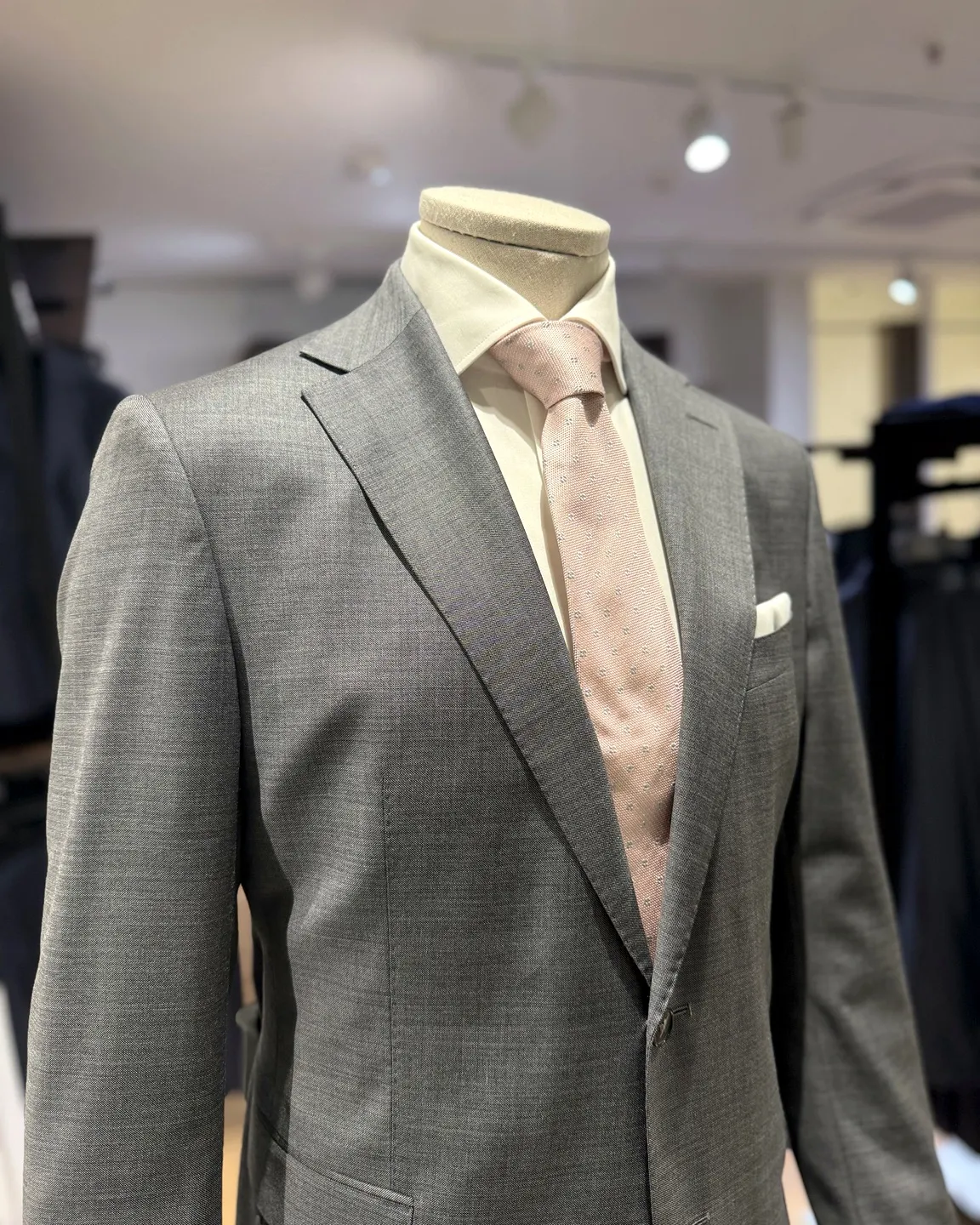 Costume gris et cravate rose poudré sur mannequin chez Roussel Hommes