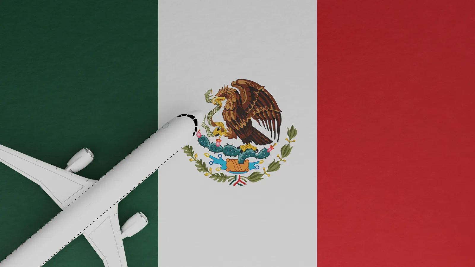 Overhead view of a white business jet beside the flag of Mexico