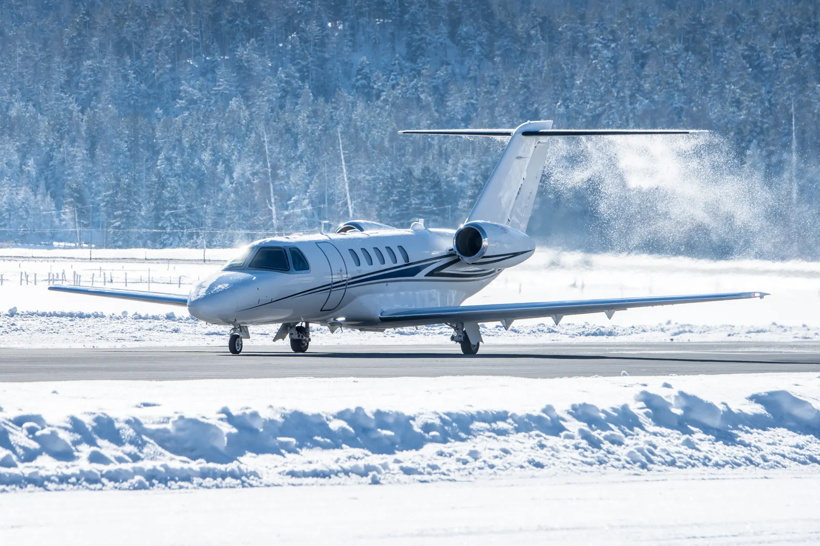 A business jet taxiing on a snow-covered runway during cold-weather winter operations