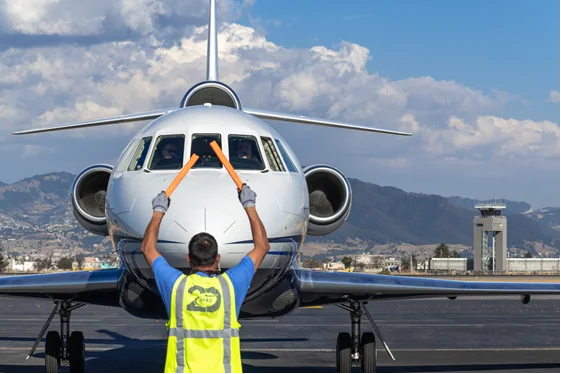 A ground marshaller directing a business jet on a ramp in Mexico