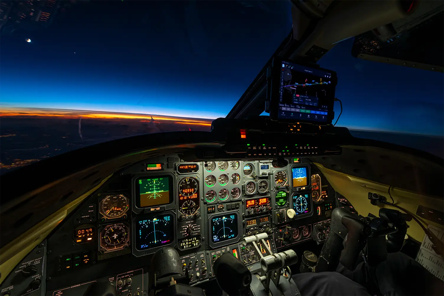 Business jet cockpit at dusk with an electronic flight bag showing an oceanic route