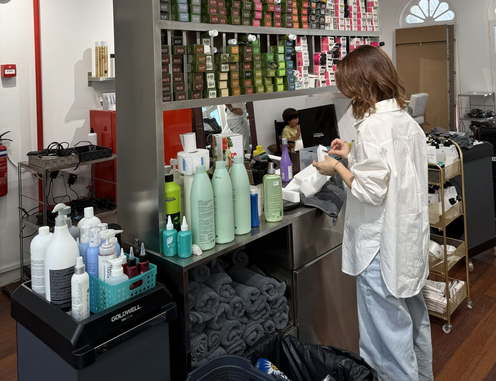 Woman with eyes closed reclining as hair is shampooed and massaged at a salon sink.