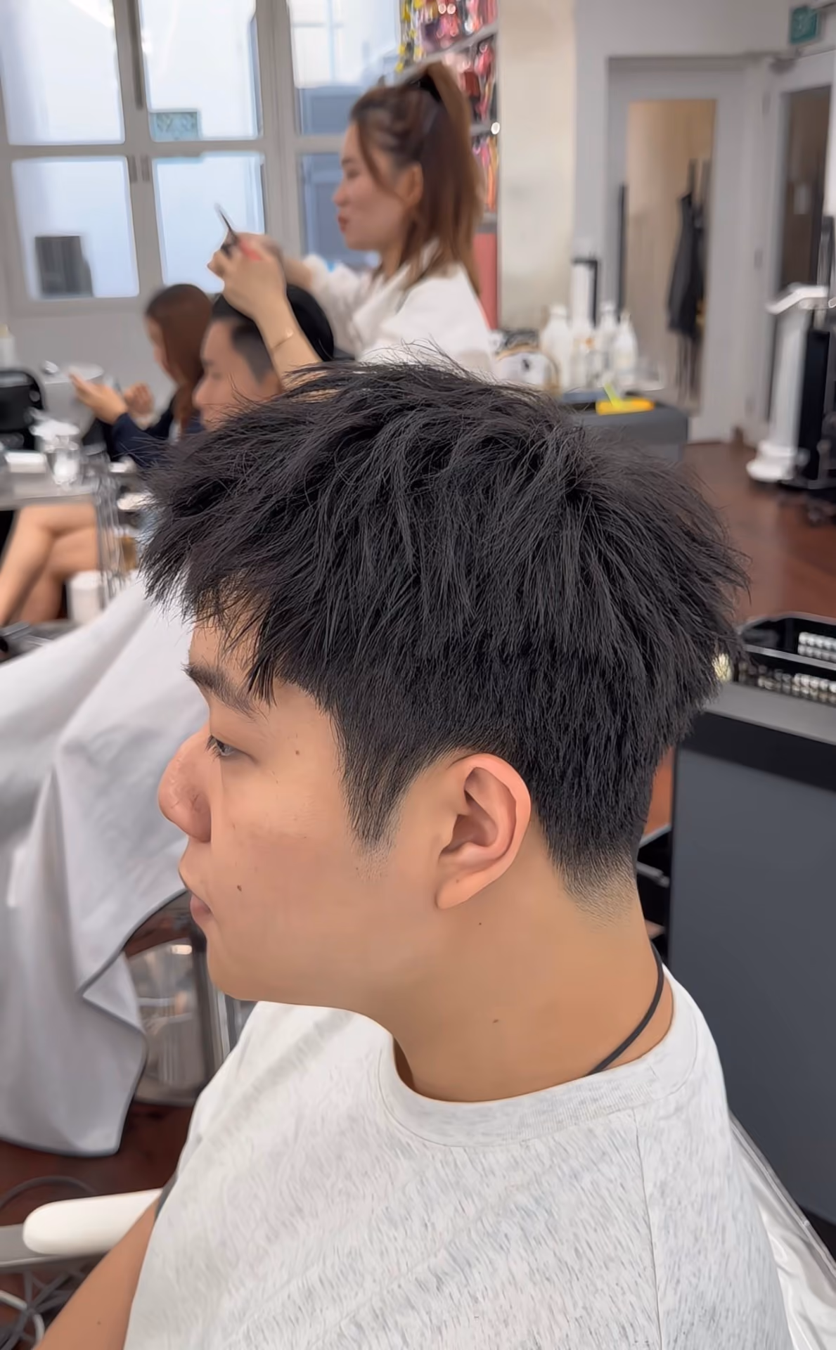 Woman with eyes closed reclining as hair is shampooed and massaged at a salon sink.