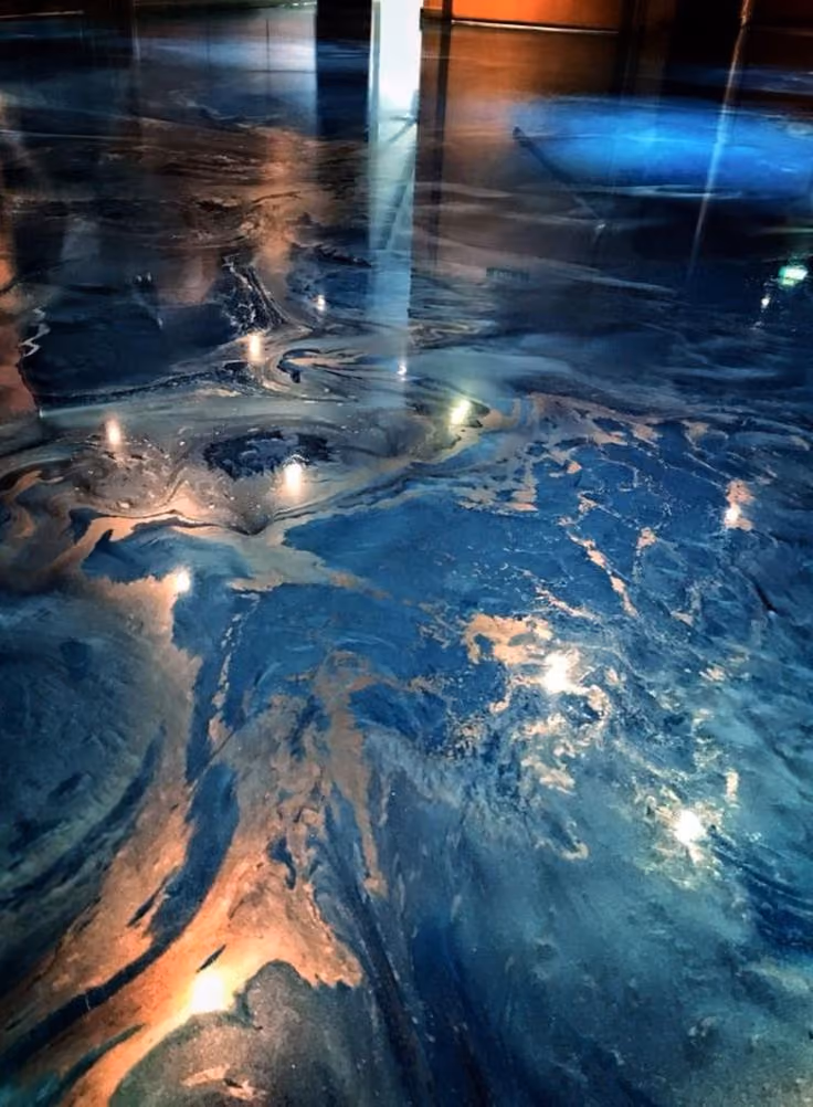 Shiny floor with swirling blue, black, and gold patterns reflecting ceiling lights and windows.