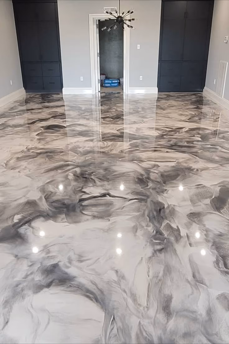 Glossy gray and black marbled epoxy floor in a modern room with dark cabinets and a chandelier.