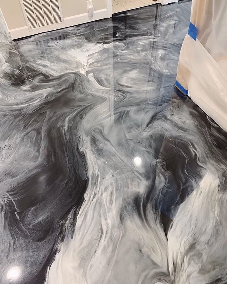 Glossy black and white metallic epoxy floor with abstract swirling patterns in a room.