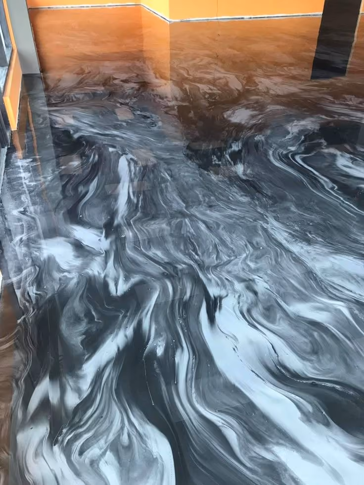 Room with glossy black and white marbled epoxy floor and orange walls reflecting in the floor.