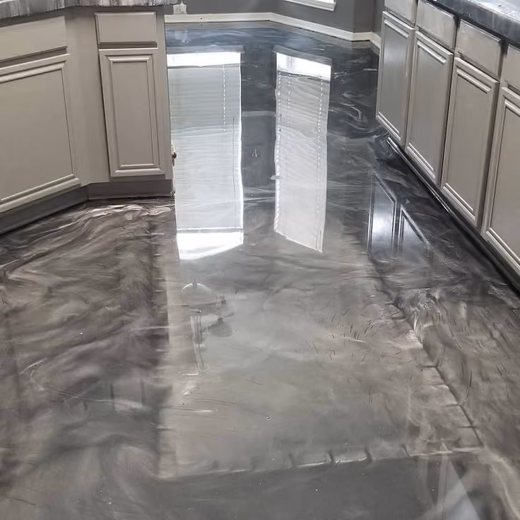 Glossy gray epoxy flooring with a swirling pattern in a kitchen with white cabinets.