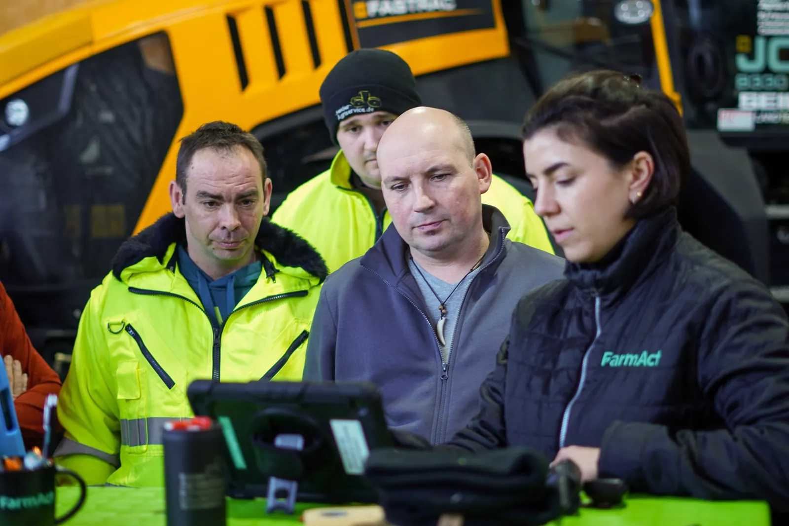 Sebastian Seider mit FarmAct Mitarbeitenden am Laptop vor einem JCB Fastrac