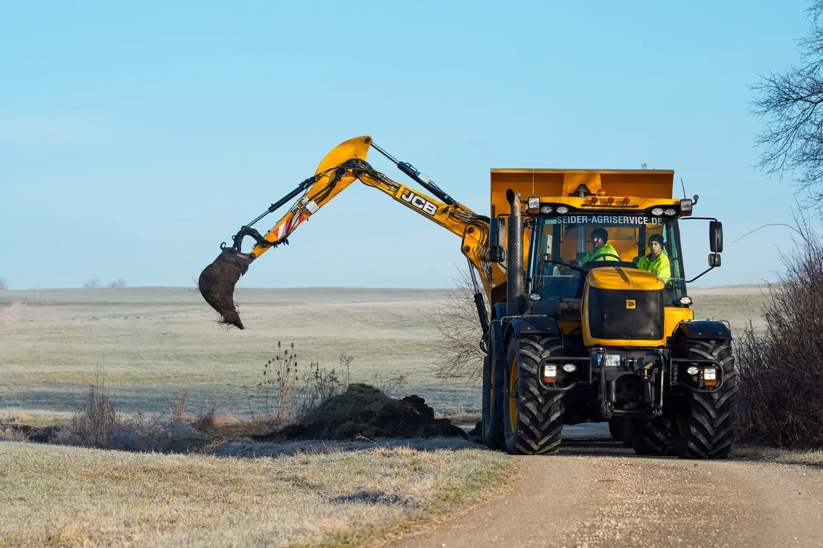 JCB Fastrac mit Anbaubagger im Einsatz auf dem Feld