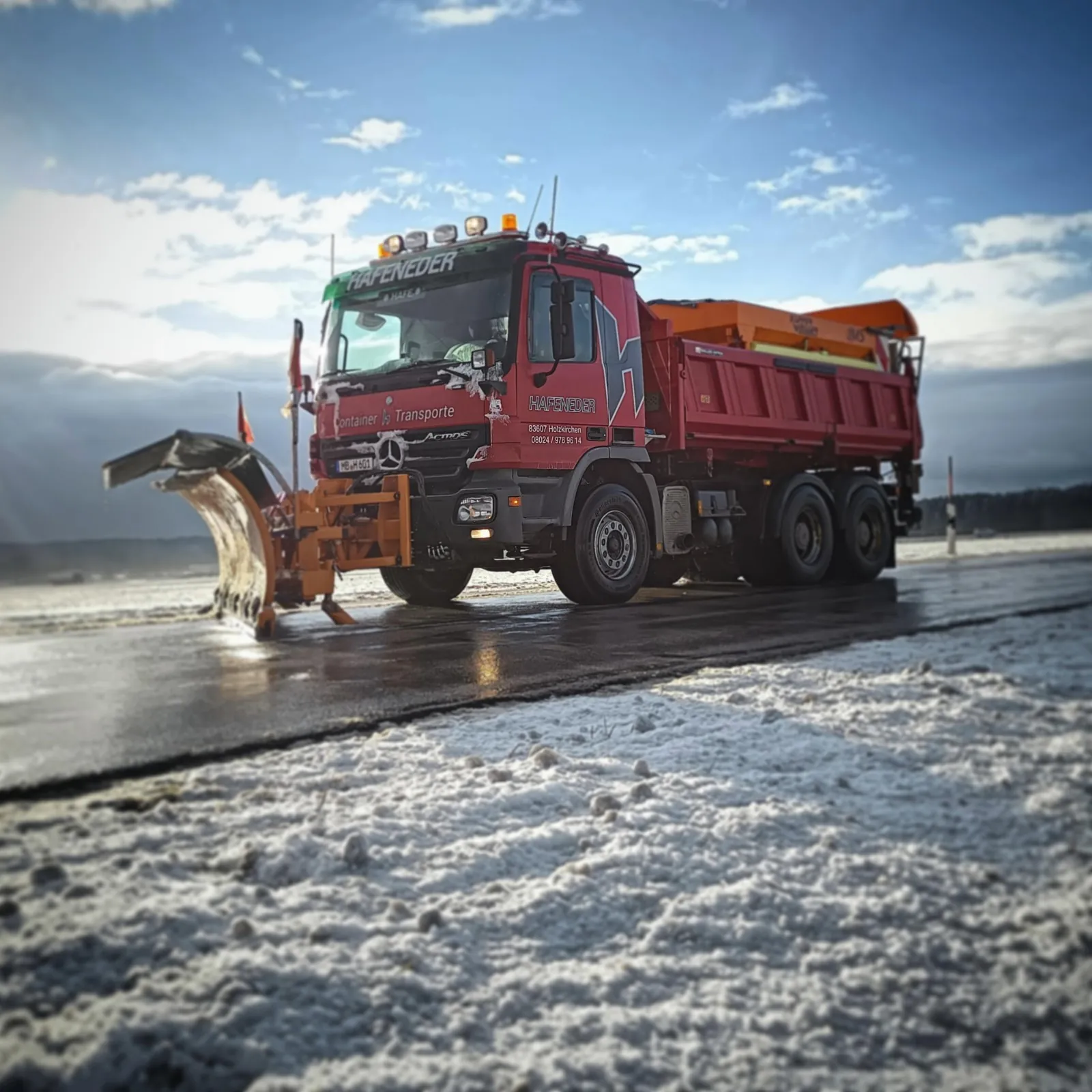 Räumfahrzeug mit Schneepflug und Streuaufbau im Winterdiensteinsatz