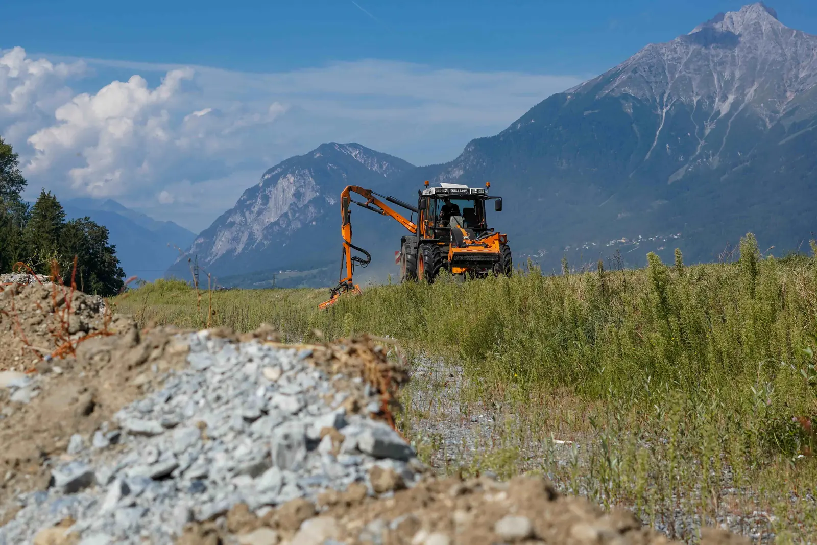 Bagger bei Landschaftspflegearbeiten vor Bergkulisse