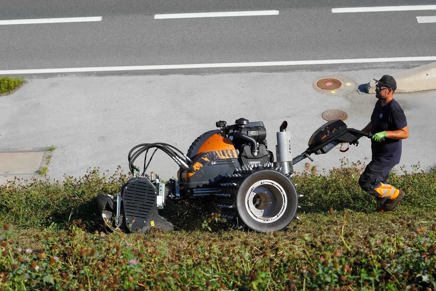 Mitarbeiter bei der Mäharbeit an einer Straßenböschung