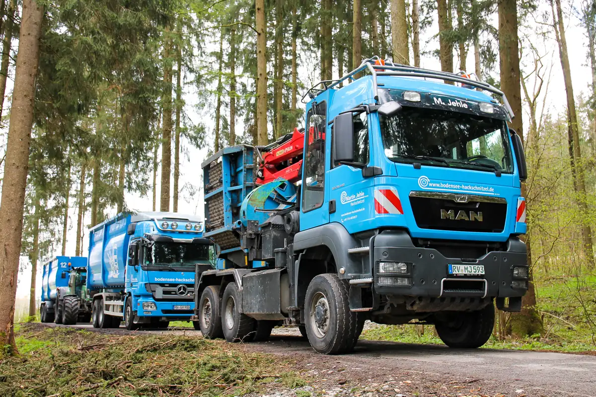 Blaue MAN-Lkw mit Ladekran beim Holztransport im Wald