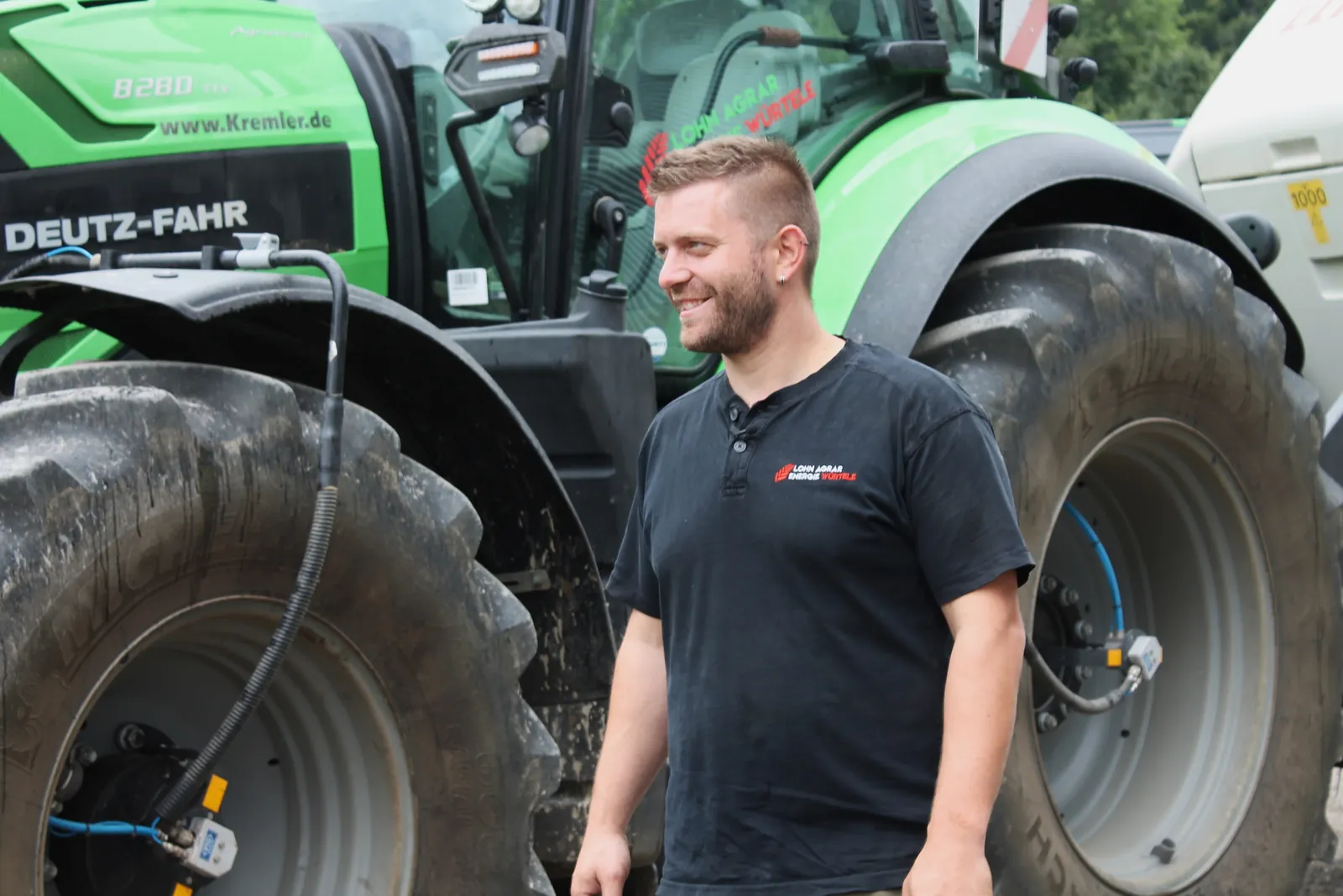 Tobias Würtele vor einem Deutz-Fahr Traktor auf dem Betriebsgelände