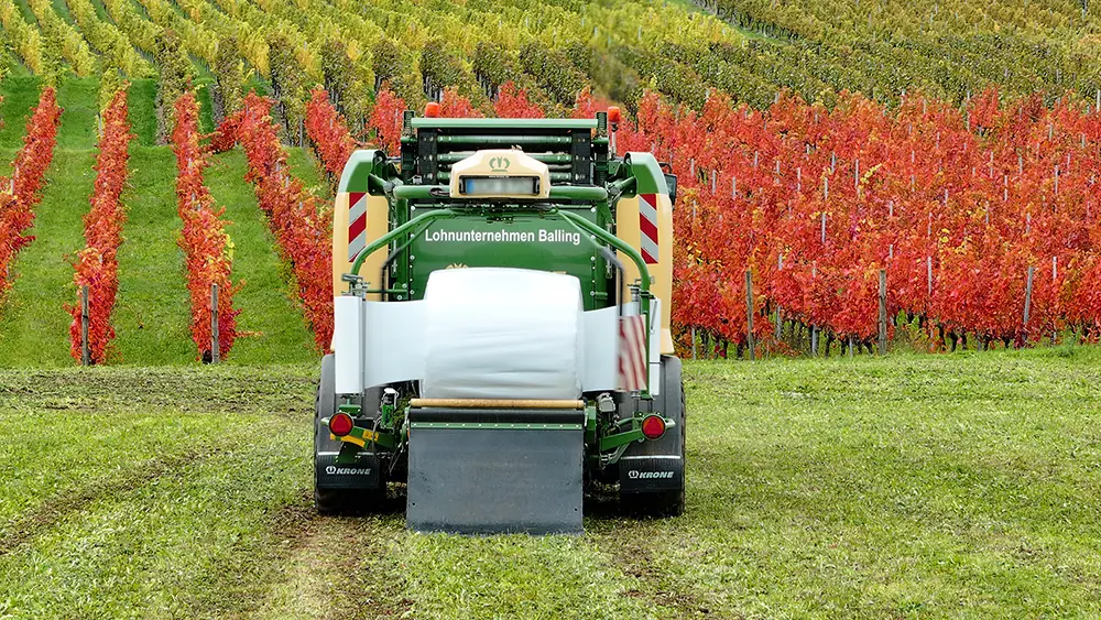 Traktor mit Rundballenpresse bei der Ernte auf dem Feld