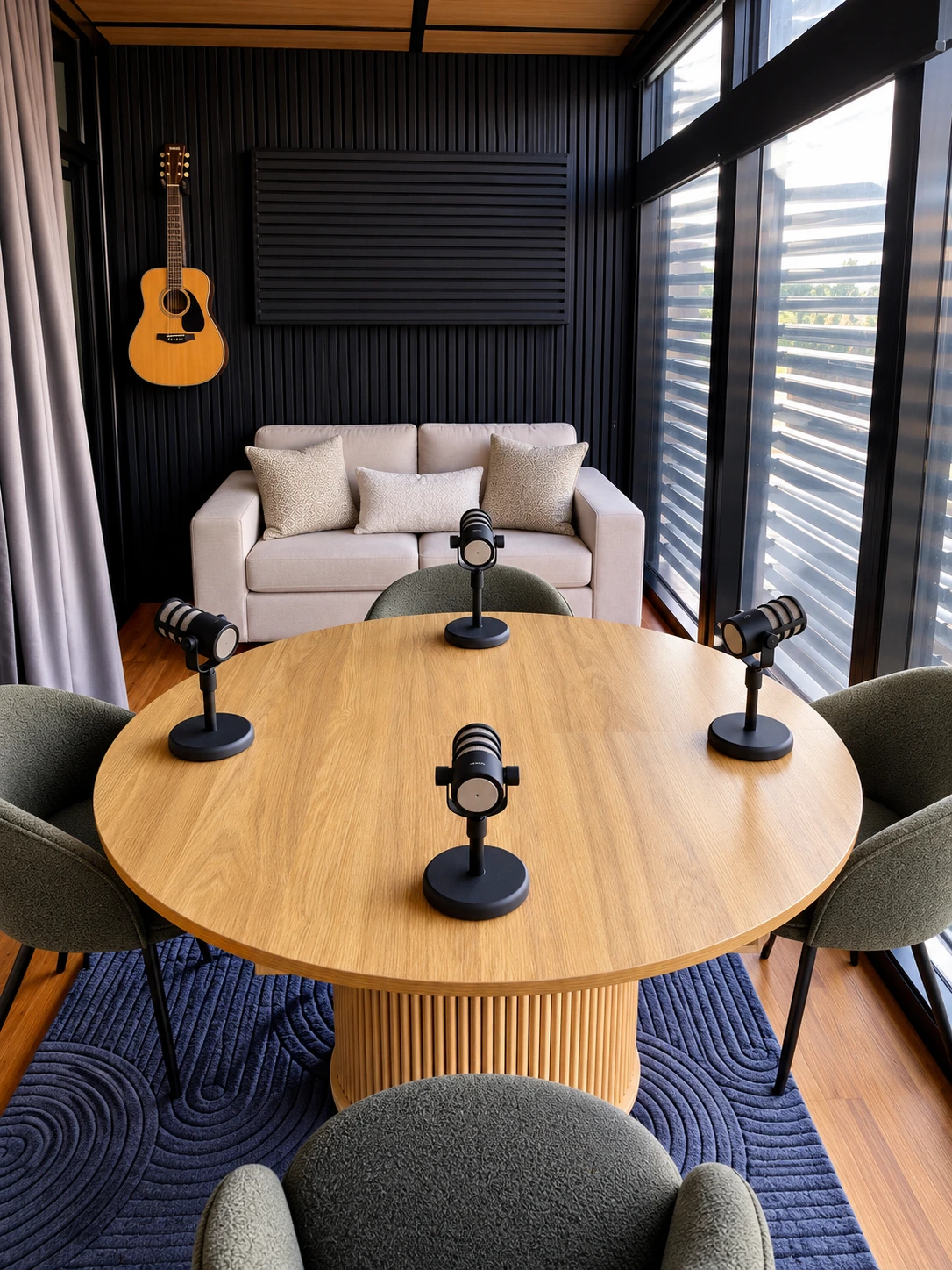 Four-microphone podcast table with sofa and wall-mounted guitar