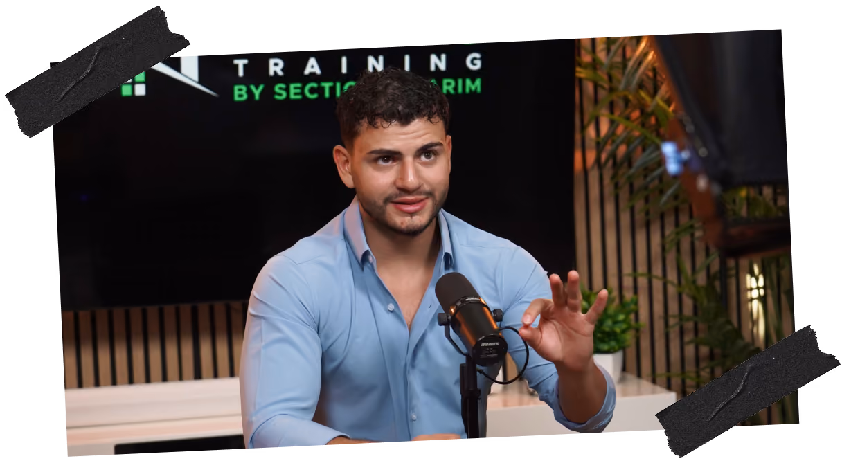 Man in blue shirt speaking into a microphone during a podcast or interview set.