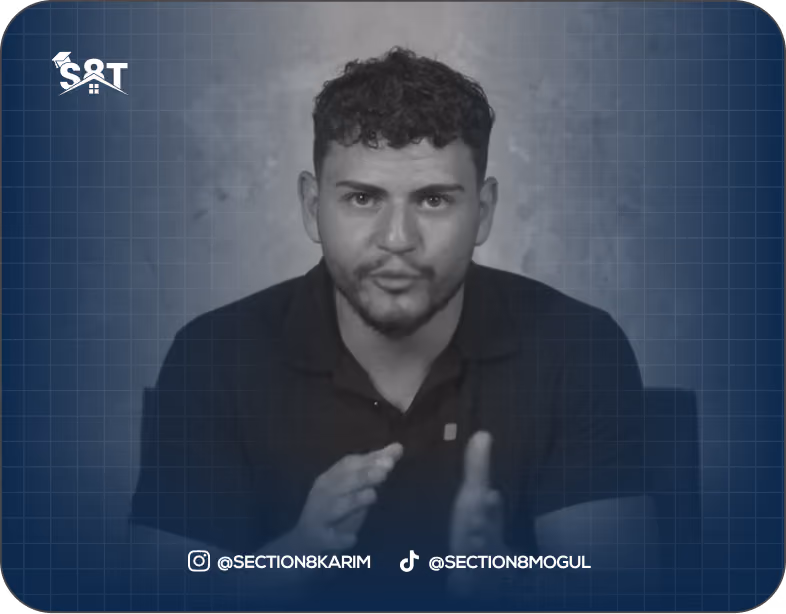 A man with short curly hair and a beard gestures while speaking, with social media handles below.