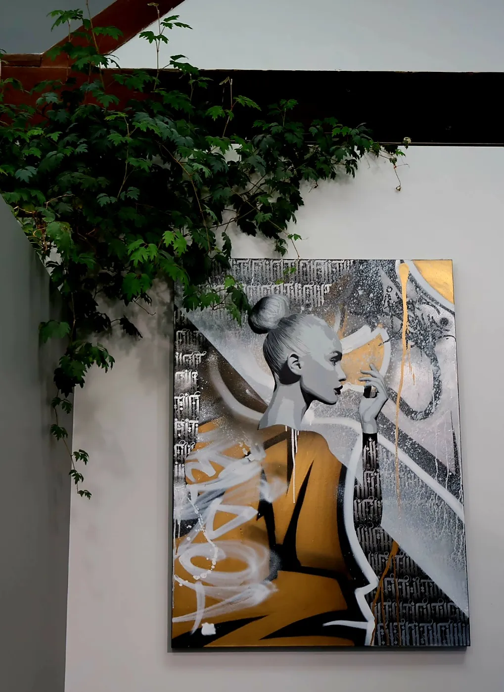 Wall art of a woman in profile with gray skin, a bun, and golden-yellow geometric shapes behind her.