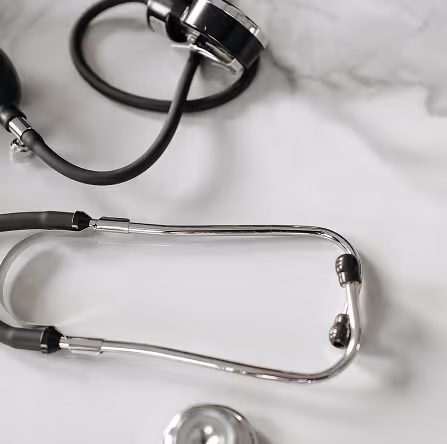 Close-up of a black stethoscope on a white surface with a marble background.