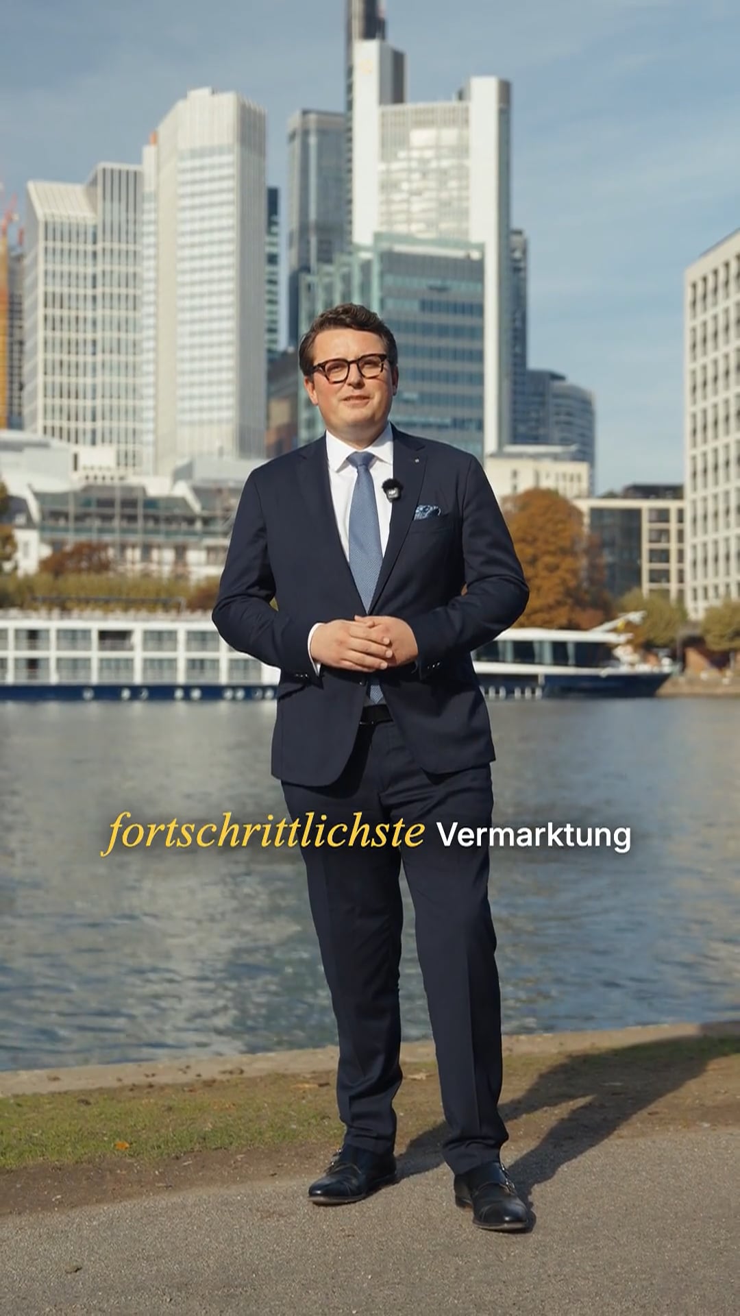Standbild aus dem Werbespot für Bettina Schmitt Immobilien: Mann im Anzug am Mainufer vor der Frankfurter Skyline