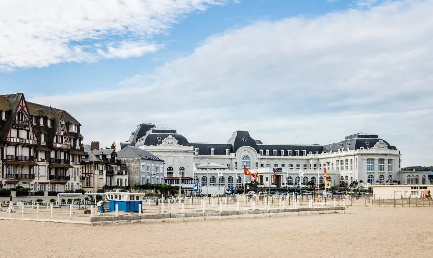 The façade of a beachfront hotel with white balconies, viewed from the sand