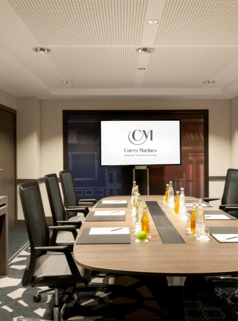 Meeting room with an oval table, black chairs and a projection screen