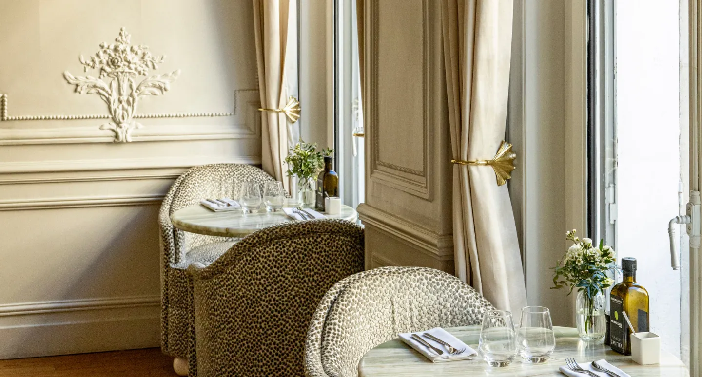 Tables de restaurant dressées avec fauteuils à motifs léopard, moulures dorées et rideaux à embrasses en laiton doré