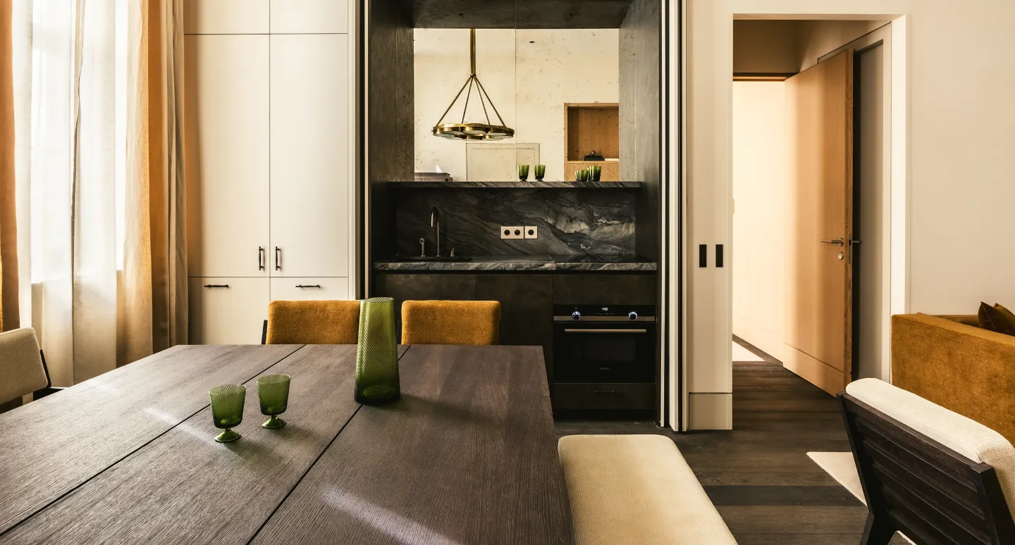 Salle à manger avec table en bois foncé, chaises moutarde et kitchenette en marbre noir veiné