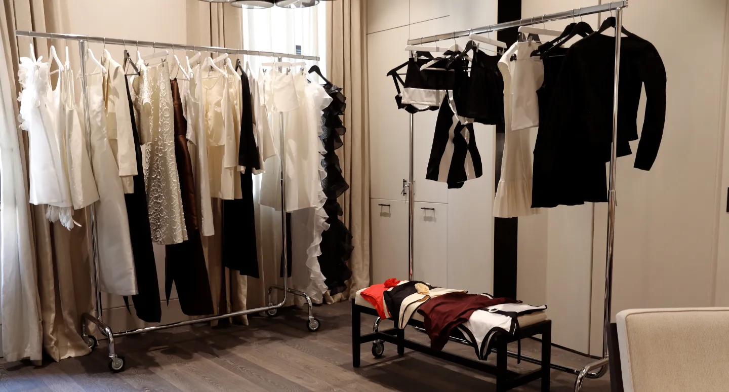 Portants de vêtements de créateurs en dentelle et satin blanc, noir et bordeaux, exposés dans une chambre lumineuse