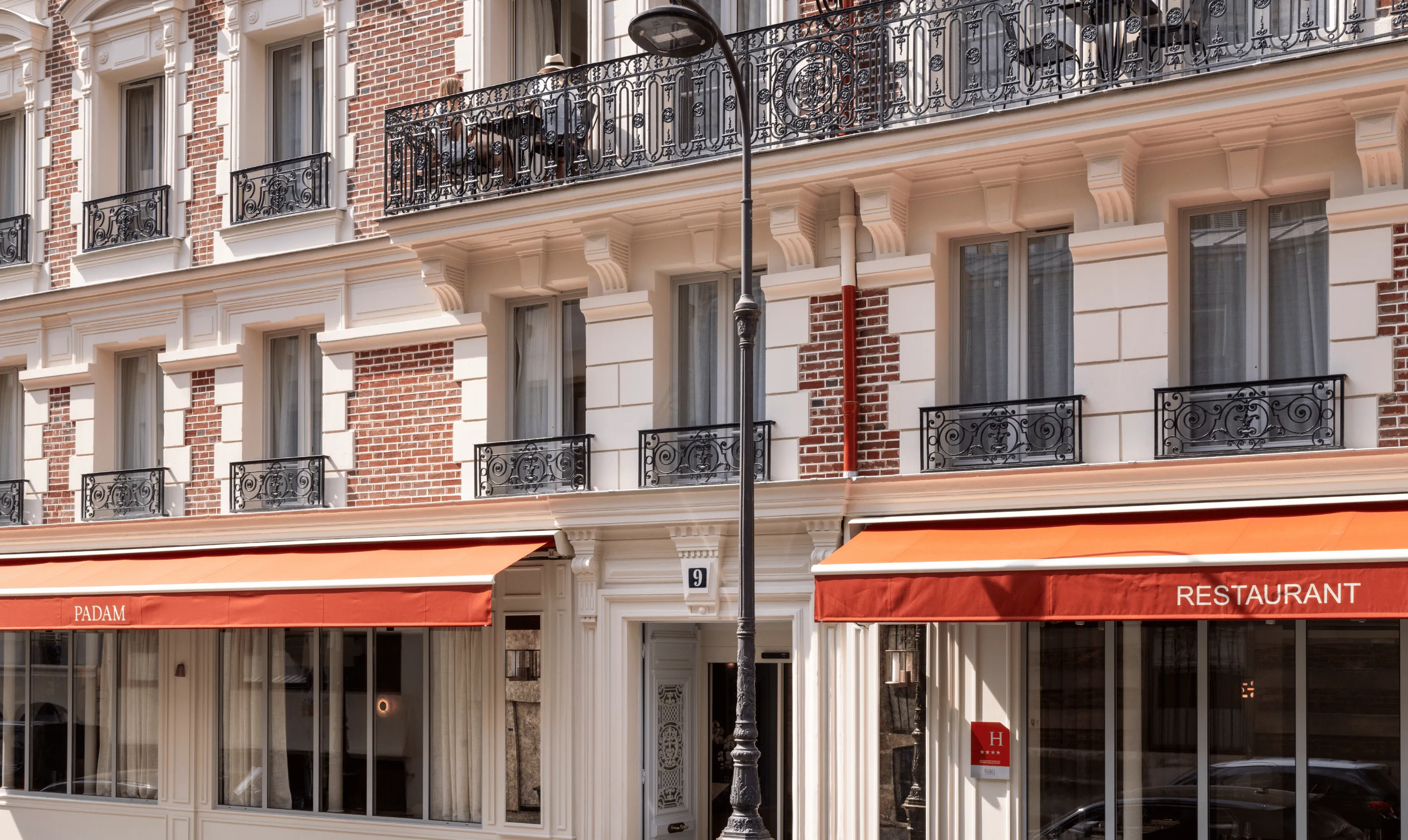 Façade d'immeuble parisien avec store orange et balcons en fer forgé