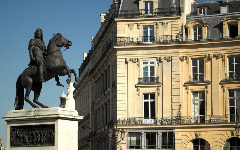 Statue équestre en bronze face à un immeuble haussmannien avec balcons en fer forgé
