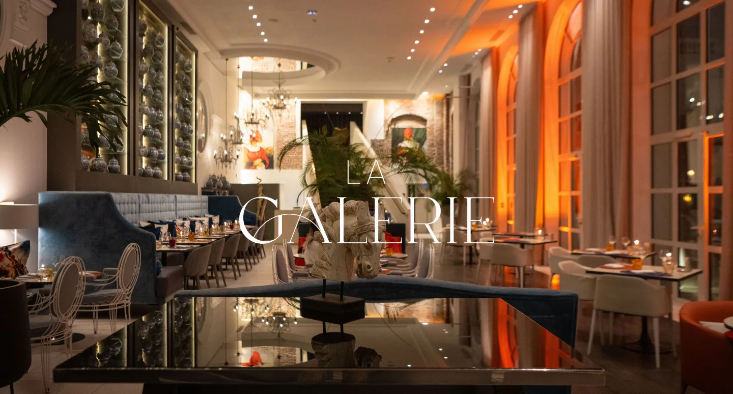 Restaurant La Galerie éclairé aux teintes orangées, avec banquettes bleues, arcades vitrées et sculpture de cheval