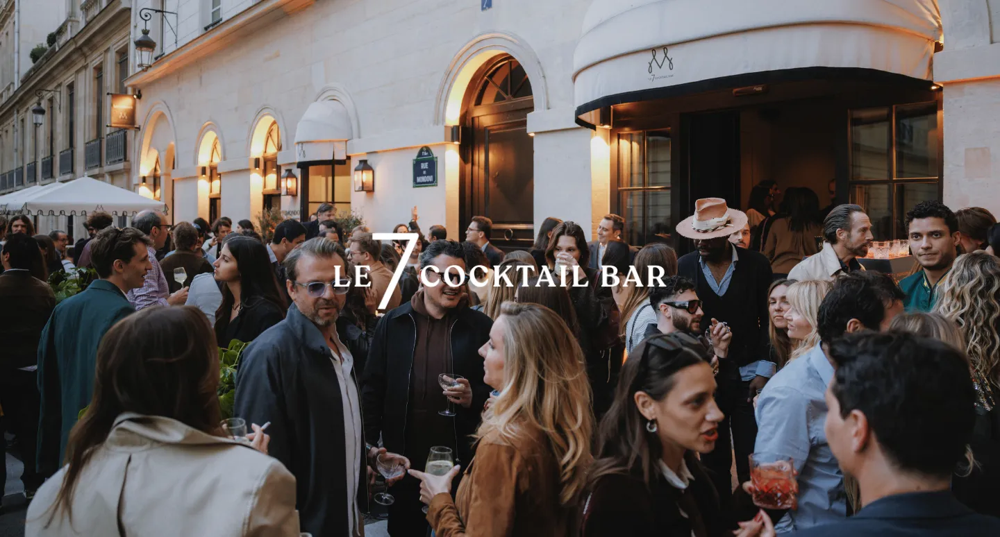 Foule animée devant la façade de Le 7 Cocktail Bar, rue de Mondovi, verres à la main en soirée