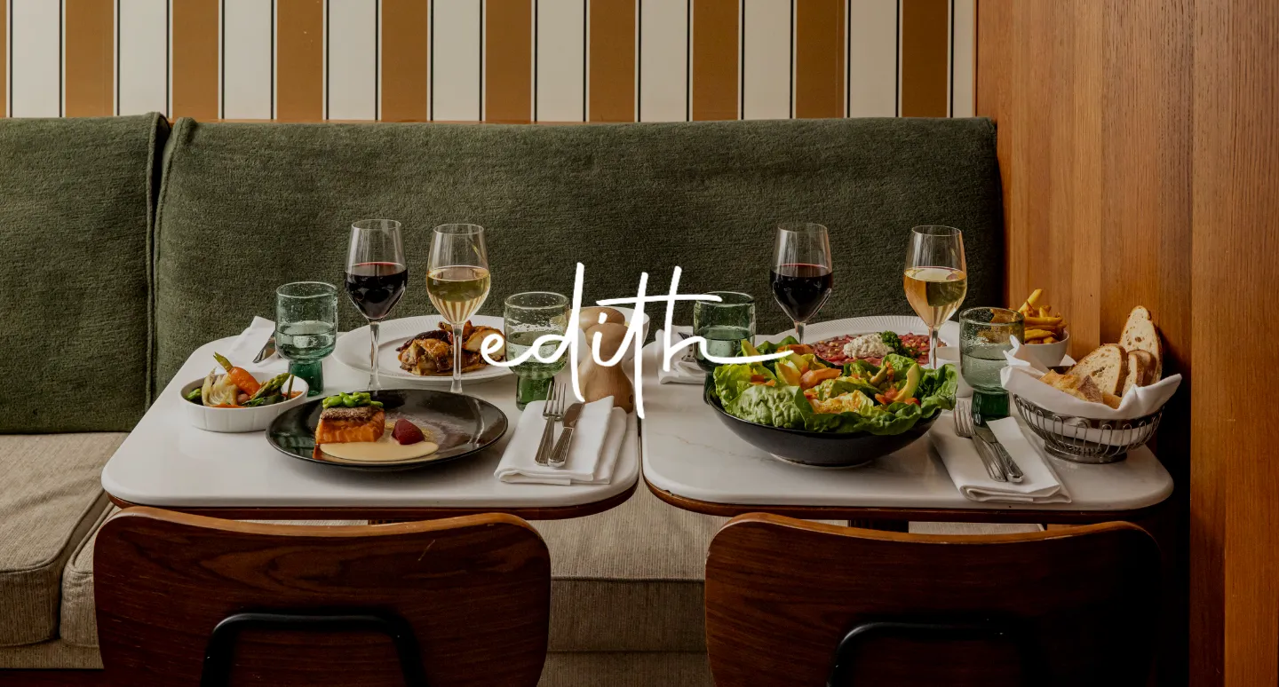 Restaurant Edith avec deux tables dressées de saumon et salade, logo manuscrit blanc superposé sur banquette verte