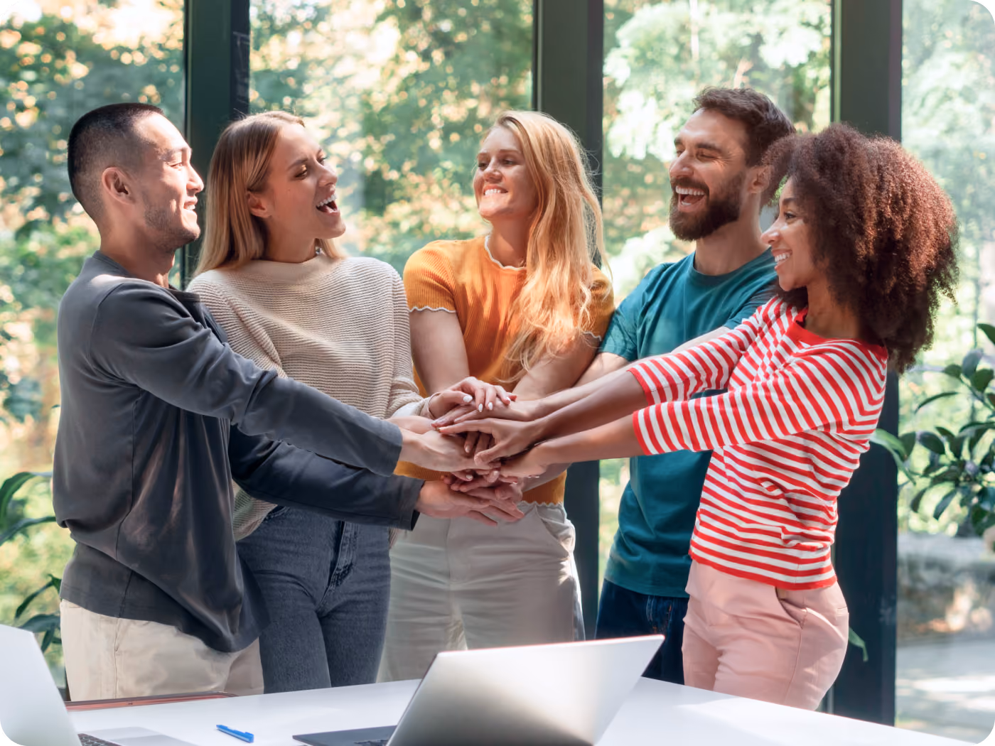 a diverse group of human beings in a corporate office setting stacking hands indicating successful results of teamwork