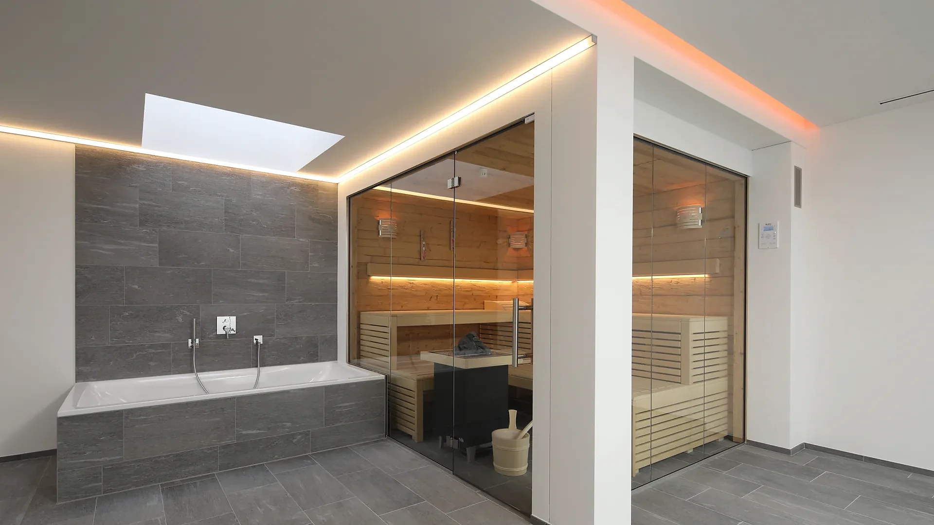 Glassauna neben Badewanne mit Steinwand und Oberlicht, Wellnessbereich im Privathaus von RR Variationen