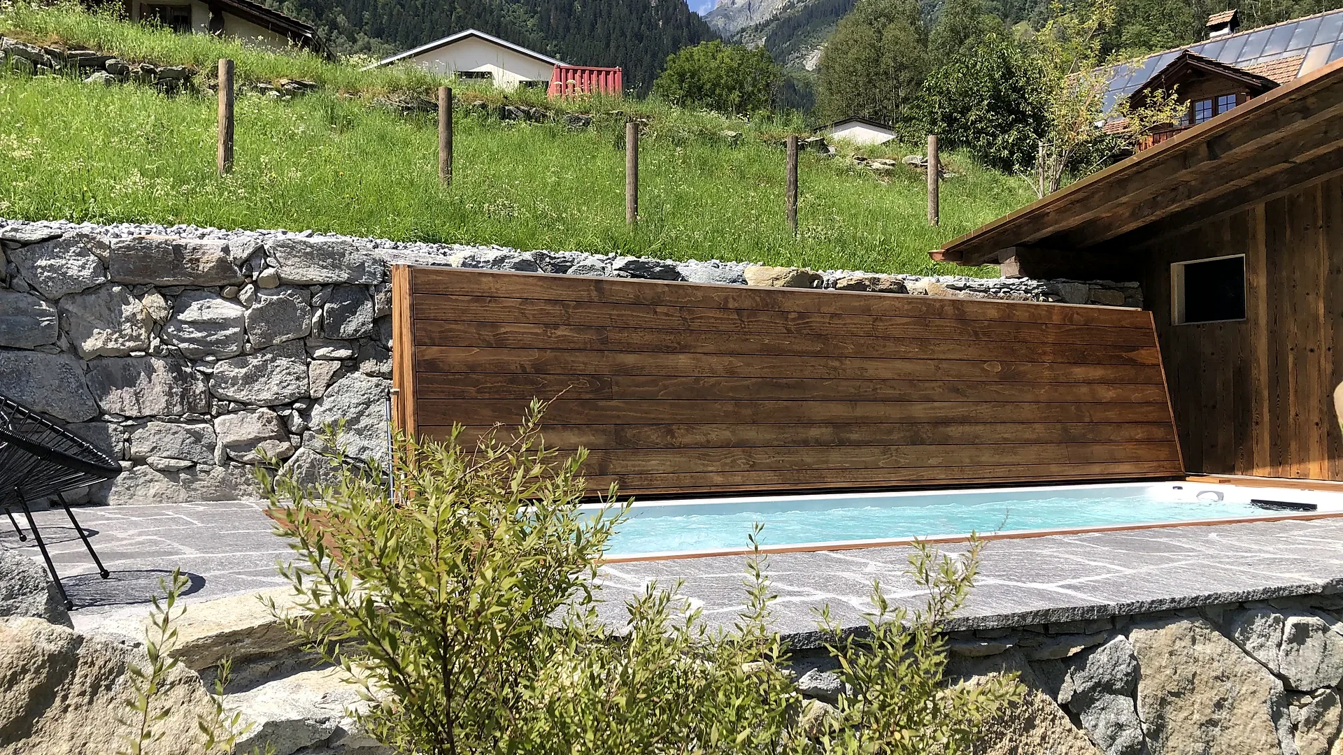 Eingelassener Pool mit Holzwand vor Natursteinmauer in Berglandschaft, Wellnesskonzept von RR Variationen