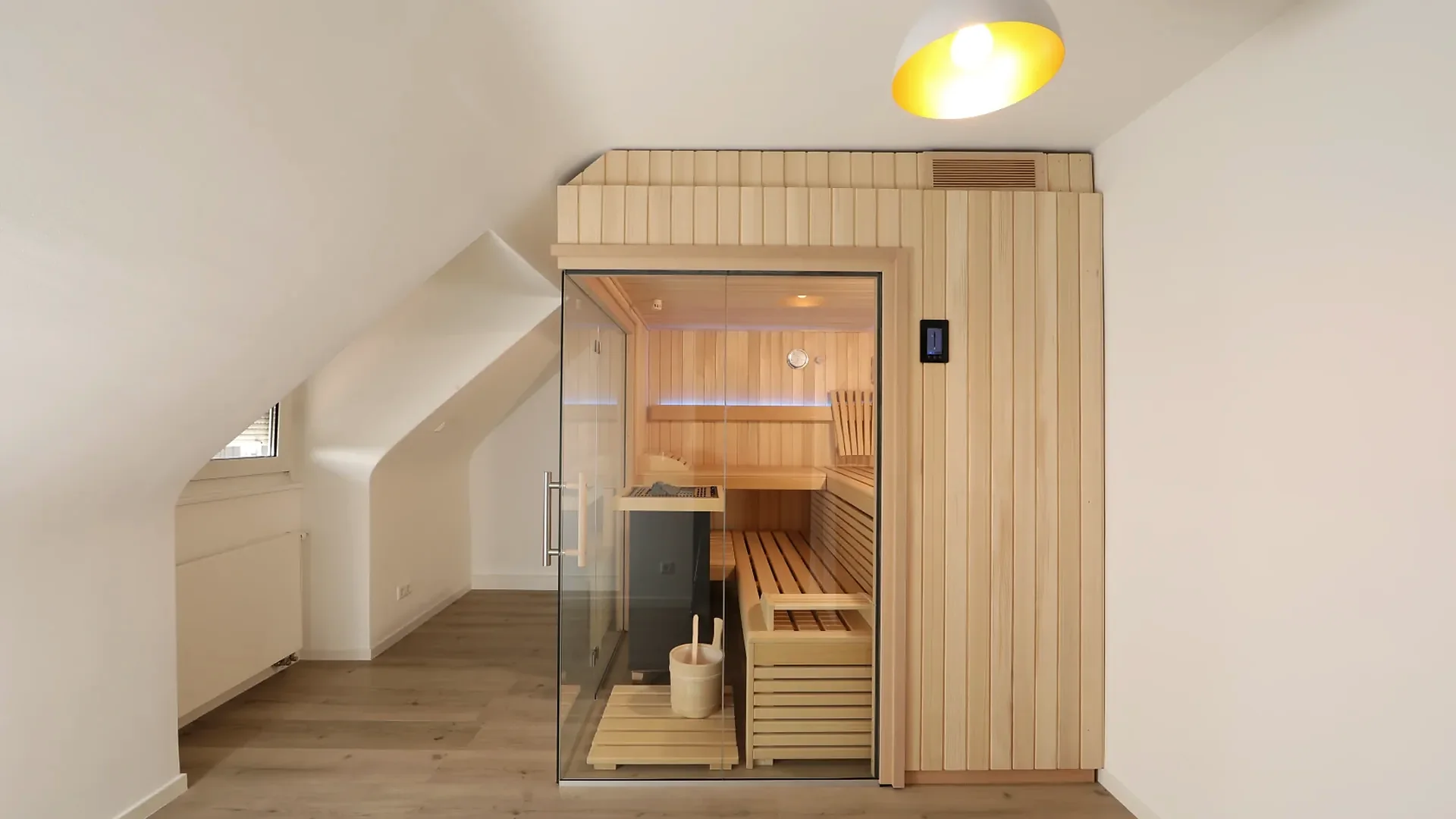 Kompakte Holzsauna mit Glastür unter der Dachschräge im Dachgeschoss, klassische Sauna nach Mass von RR Variationen