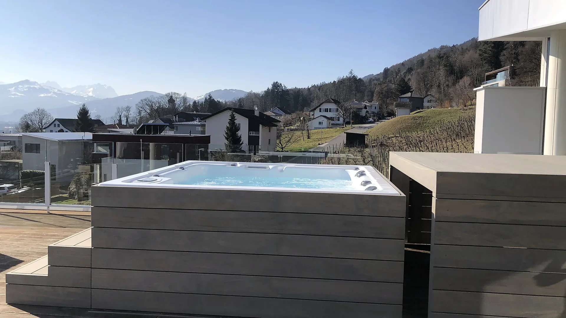 Offener Whirlpool mit grauer Holzverkleidung auf einer Dachterrasse mit Alpenblick, Abdeckung nach Mass von RR Variationen