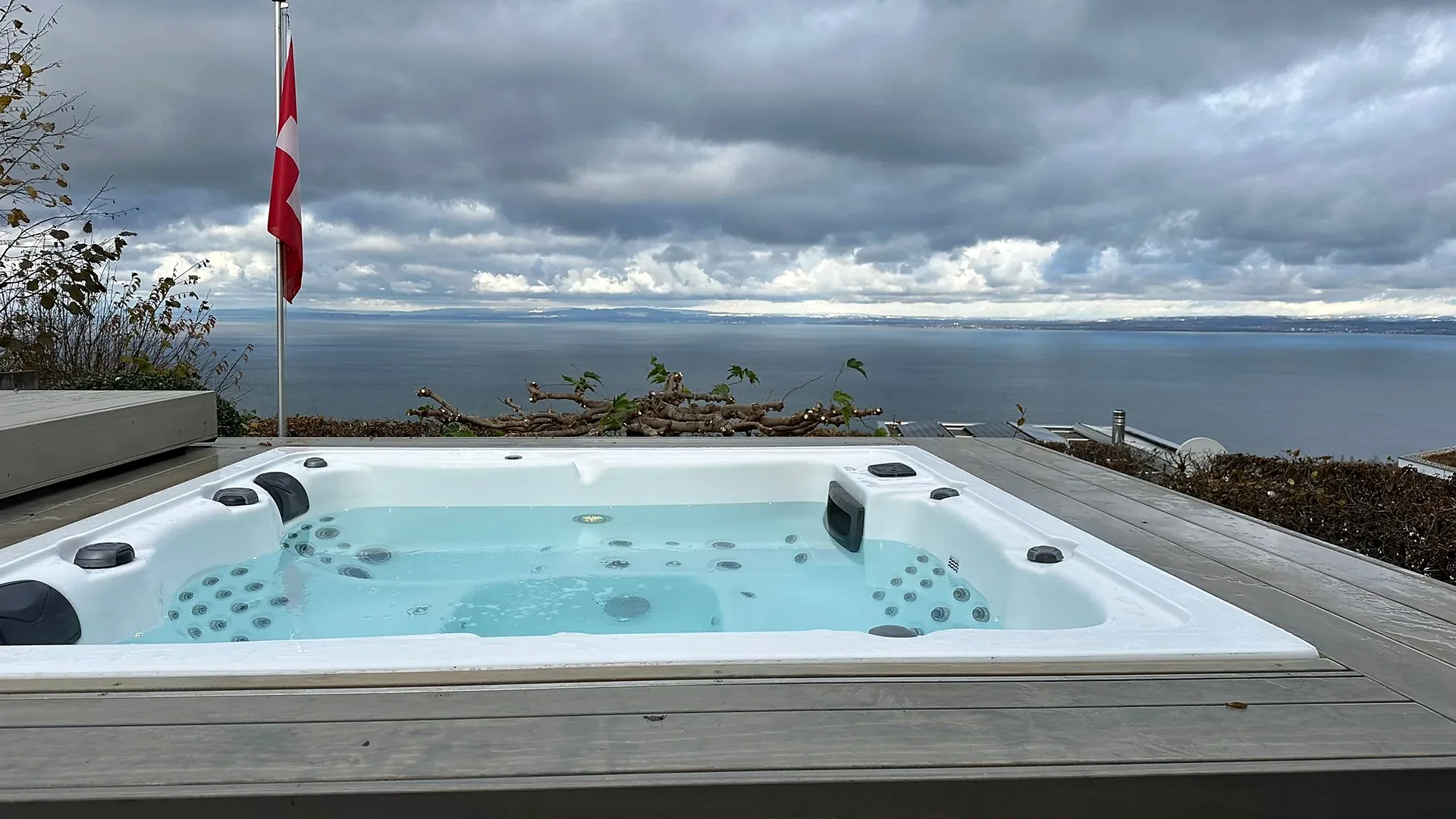 Eingelassener Whirlpool auf Holzterrasse mit Seeblick und Schweizer Fahne, Whirlpool nach Mass von RR Variationen