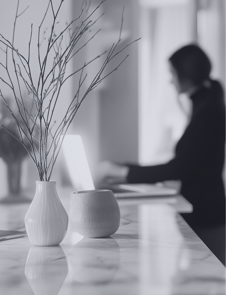 Woman working at a desk beside a vase of branches